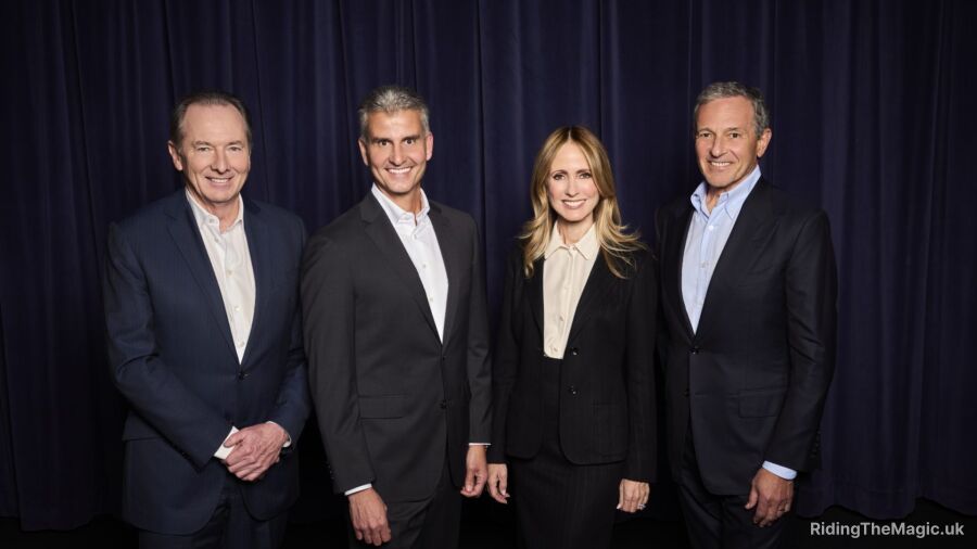 Four people in suits standing next to each other in front of a blue curtain