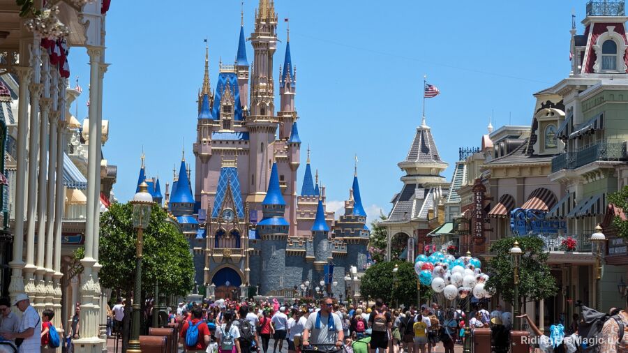 Disney World's Cinderella Castle with a crowd of people walking around in the foreground