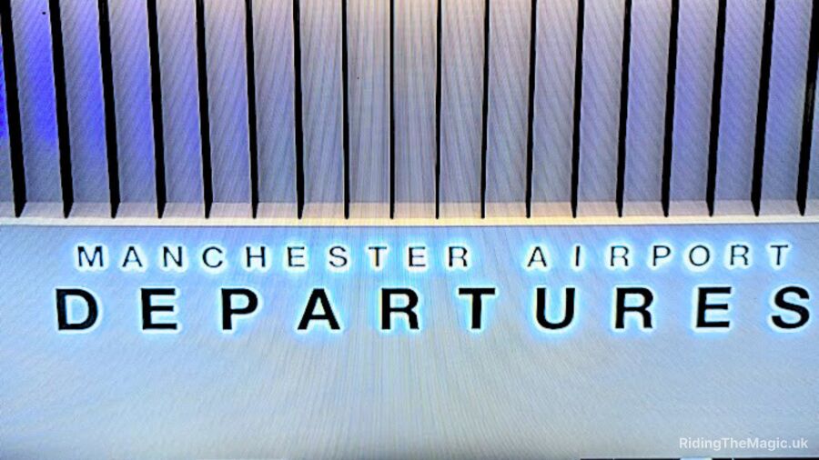 A sign for Manchester Airport Departures with a blue background and white lettering