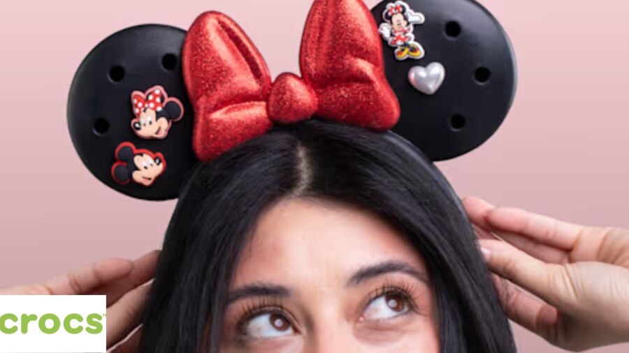 A woman wearing a Minnie Mouse-themed Crocs headband with a red bow and Mickey Mouse stickers