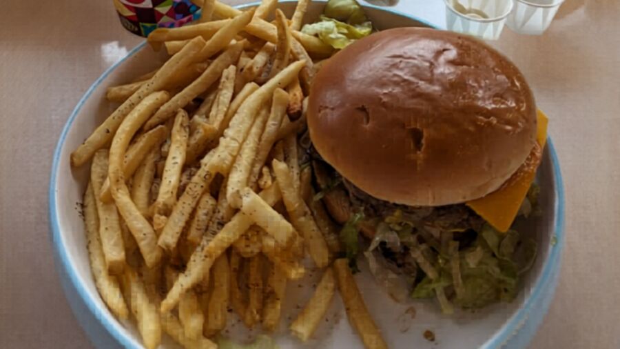A burger with fries and a side of lettuce on a white plate