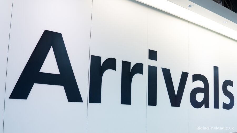 Arrivals sign on a white wall with a light on top of it