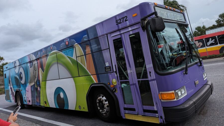 A purple bus with a Toy Story theme is parked on the side of the road