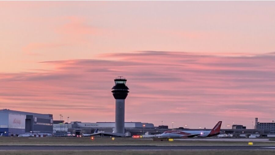 A plane is parked on the runway at an airport during sunset