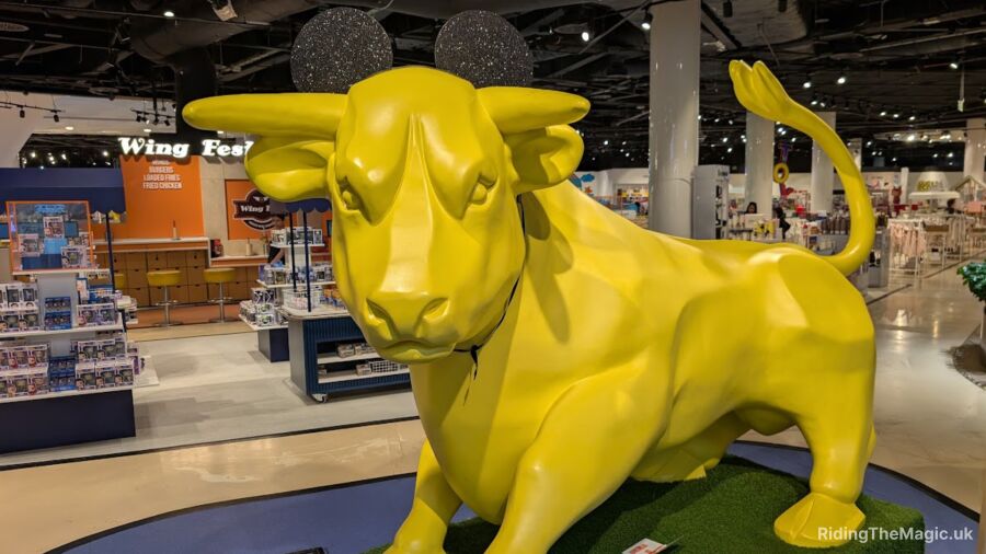 A yellow Birmingham bullring bull statue with Mickey Mouse ears is in a store