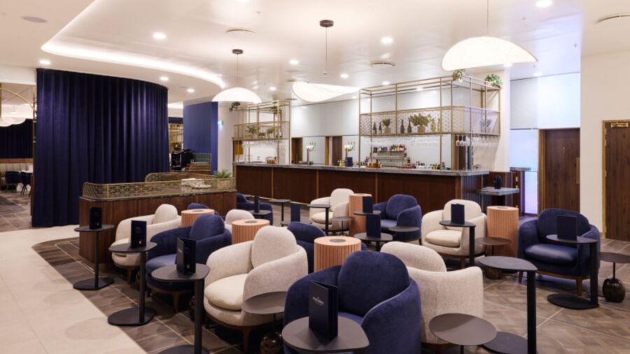 Interior of a lounge with blue and white chairs, tables, and a bar