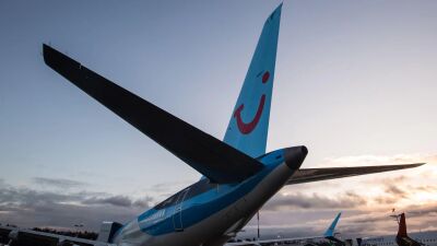 The tail of a blue and white airplane with a red smiley face on it