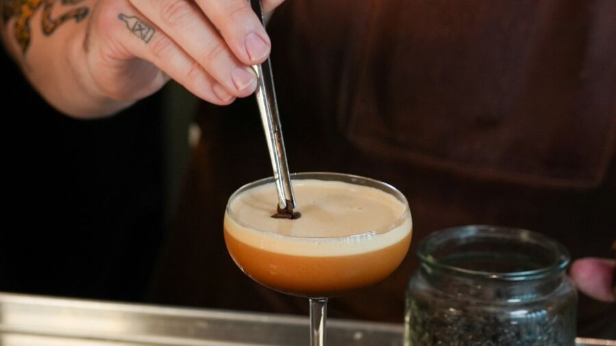 A bartender is garnishing a cocktail with a chocolate stick