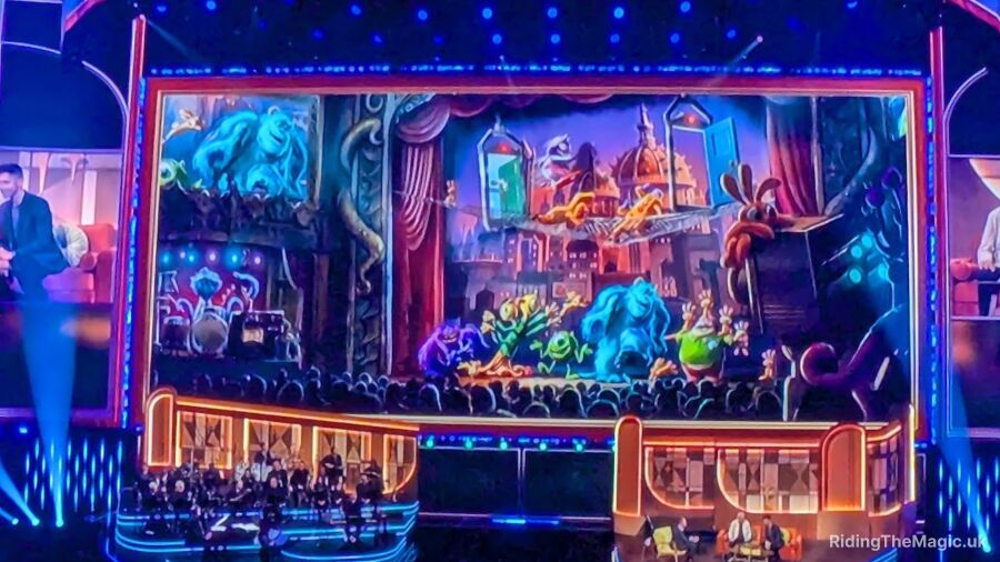 A stage with a large screen showing animated characters and a crowd watching