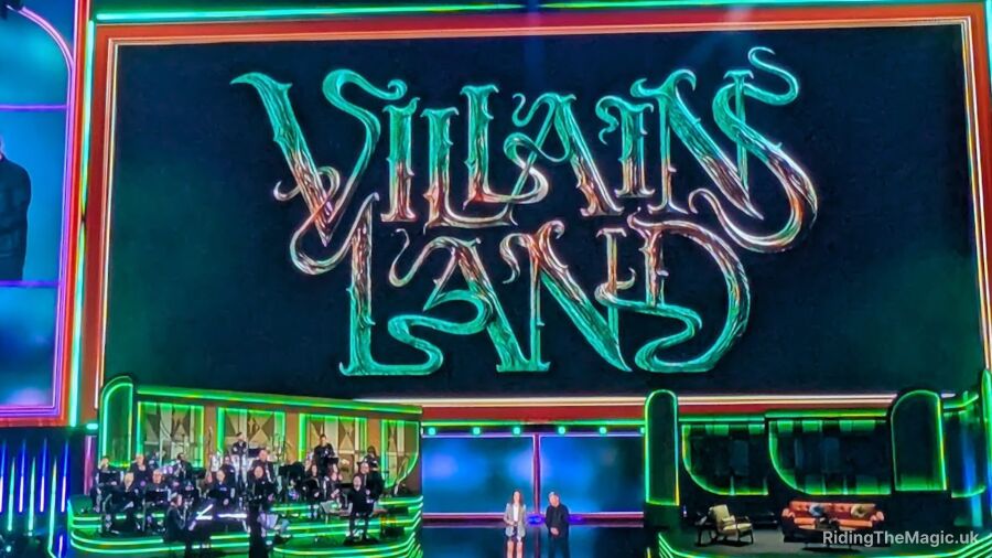 Villains Land logo on a stage with a band and two people standing