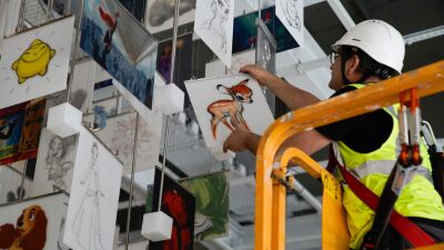 A man wearing a hard hat works on a piece of art