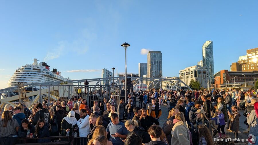 A large crowd of people gathered in front of a cruise ship