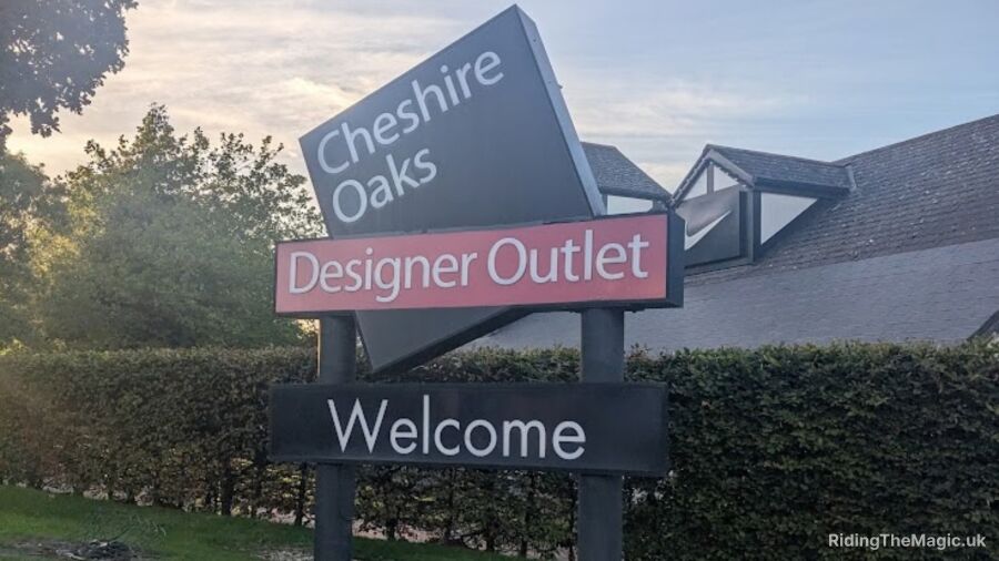 Cheshire Oaks Designer Outlet sign in front of a building and bushes
