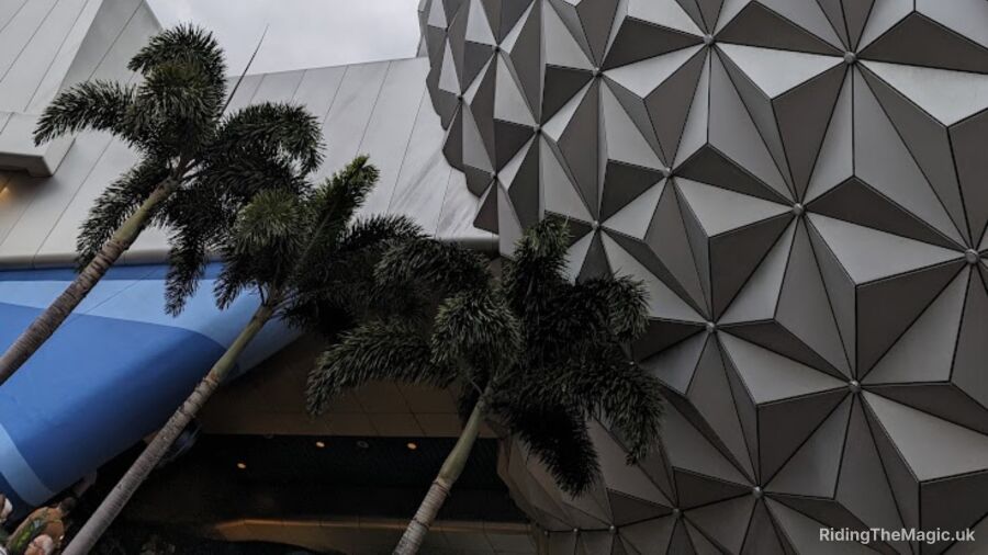 Epcot Center entrance with palm trees and a futuristic building in the background