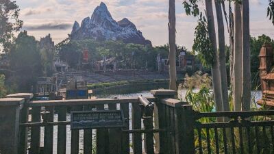 A wooden fence with a view of Expedition Everest mountain and a lake in the background