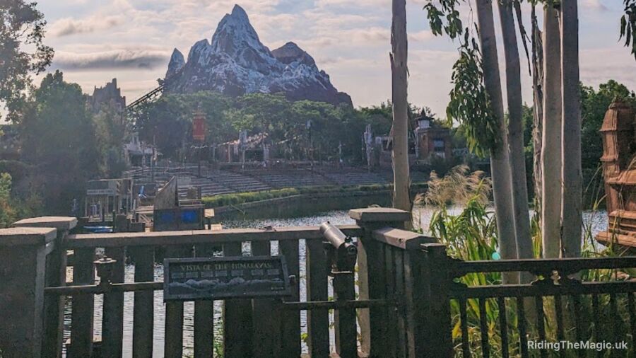 A wooden fence with a view of Expedition Everest mountain and a lake in the background