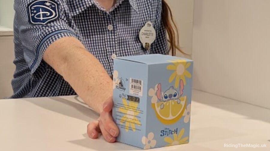 Disney Store Cast Member holds a box of Stitch merchandise at a Disney store