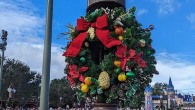 A Christmas wreath with a red ribbon is hanging on a street light