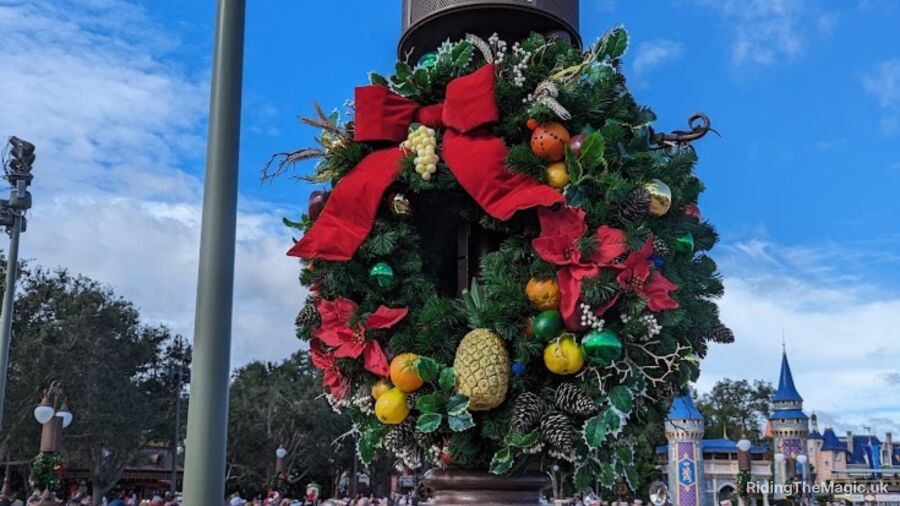 A Christmas wreath with a red ribbon is hanging on a street light