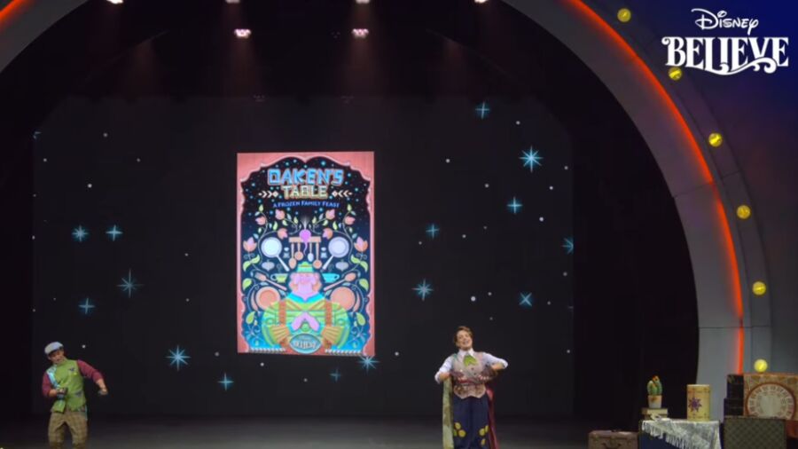 Two people on stage with a poster behind them that says 