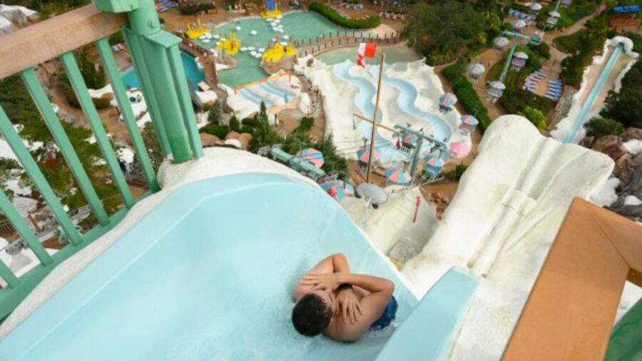 A person is sliding down a blue water slide at a water park