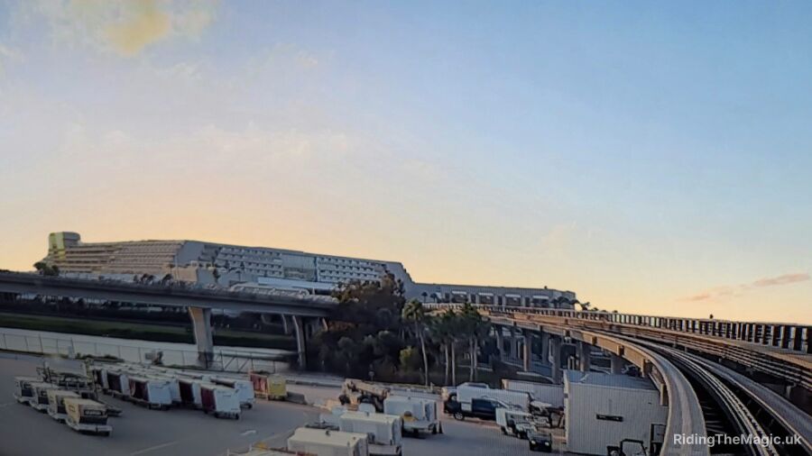 A view of an airport with a bridge, vehicles, and a sunset sky