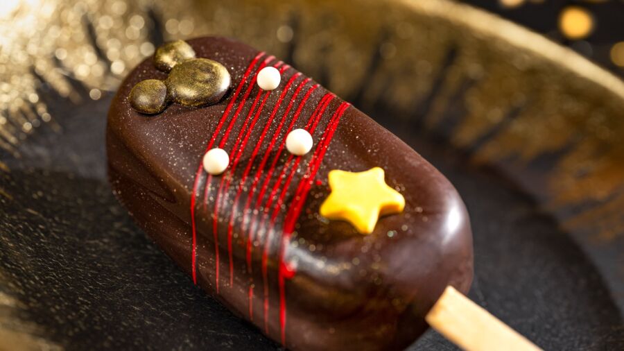 Chocolate popsicle with red stripes, white dots, and a yellow star on a gold background