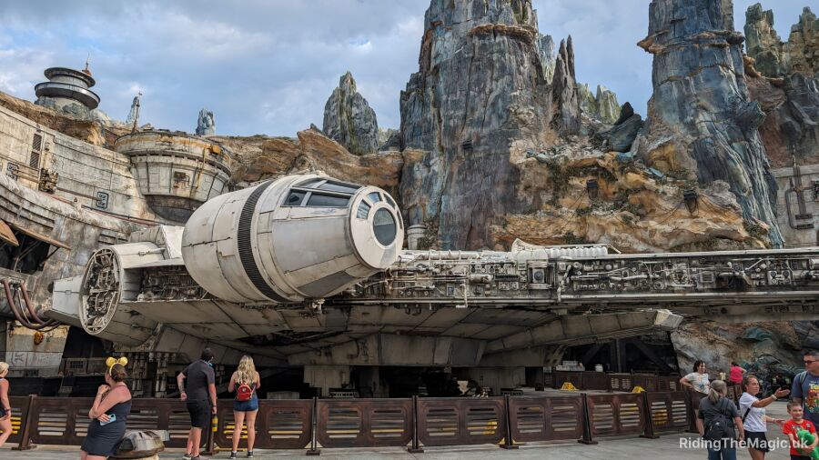 People standing around the Millennium Falcon in front of a rocky mountain Galaxy's Edge