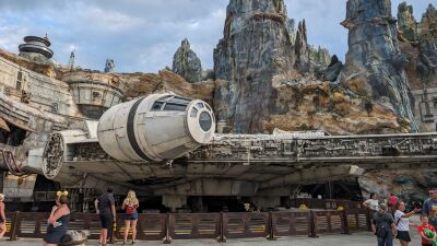 People standing around the Millennium Falcon in front of a rocky mountain Galaxy's Edge