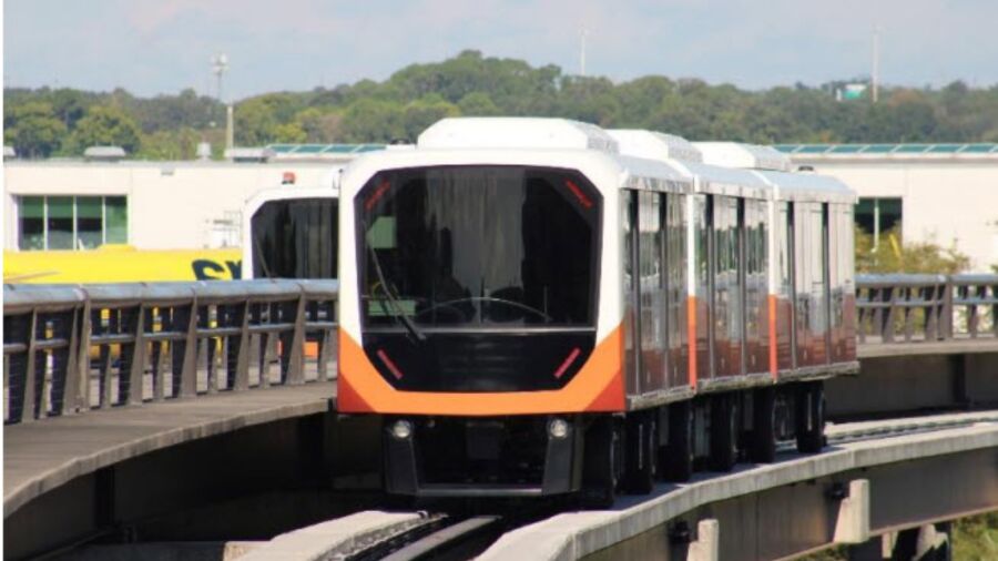A monorail is traveling on the tracks in front of a building