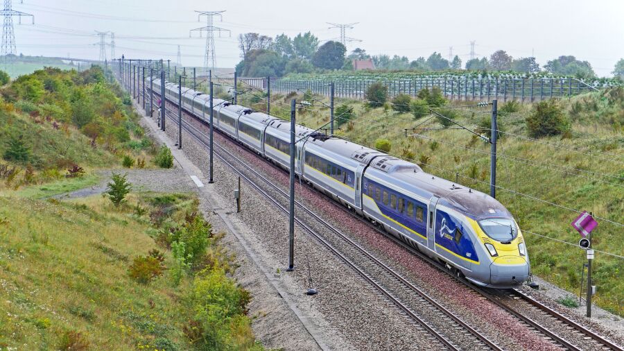 A train is moving on the railway track in the countryside with green grass